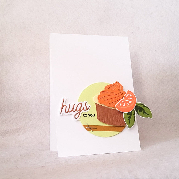 A clean and simple handmade card with the word hugs and an image of a cupcake.