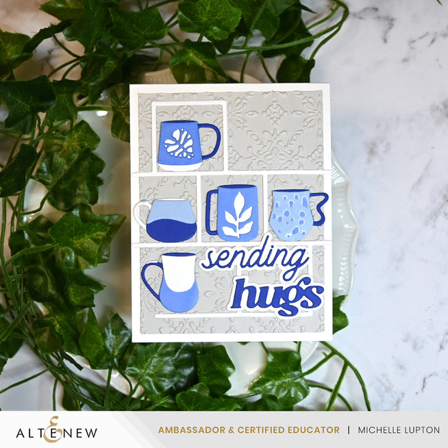 Altenew Warm & Cozy Sentiments die set with intricate dies, featuring mug and Moroccan tile designs in a detailed craft image.