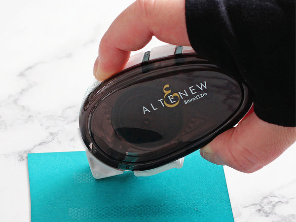 Hold the applicator at a slight angle and firmly glide it across your paper to roll out the tape.