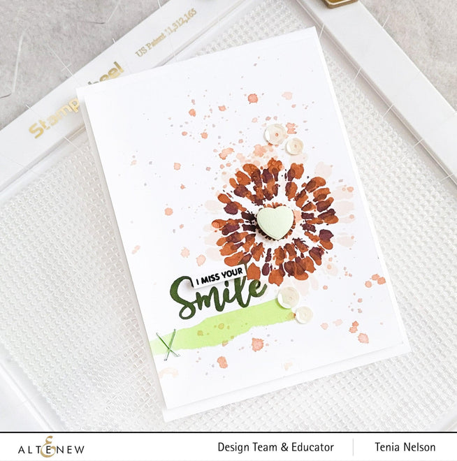 Altenew Stampwheel 1.0 Meta tool with colorful stamps and ink pads for crafting and stamping projects.